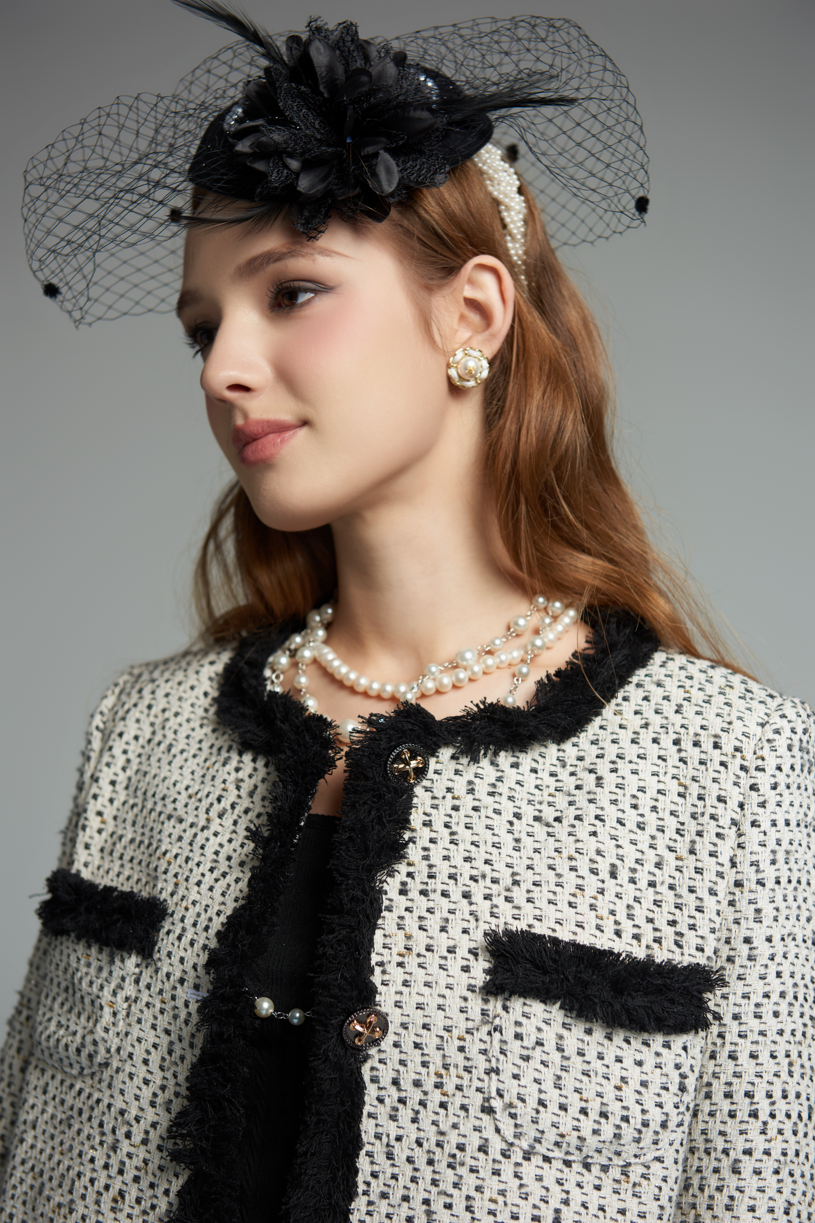 Woman wearing a black and white outfit with a decorative headpiece on a gray background